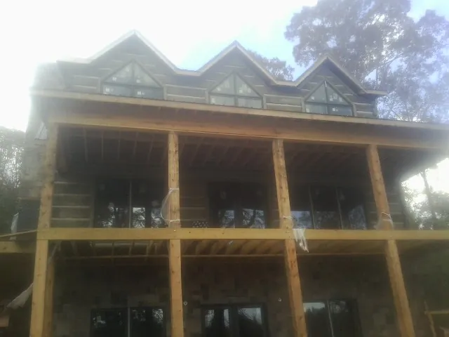 Dormers and porch framing on a large log home under construction — Roof Coating work by our crew in Port Barre