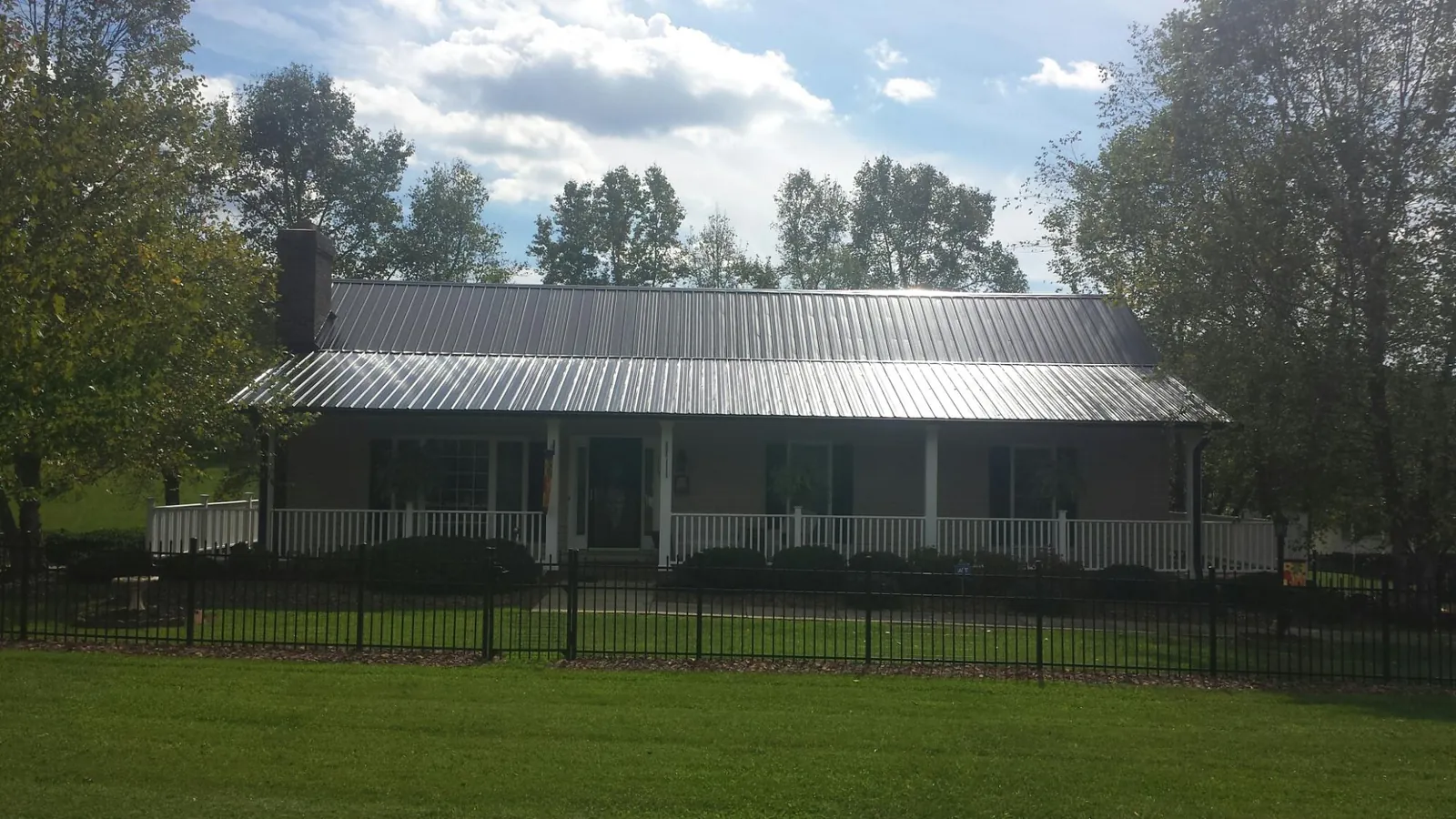 Gray metal roof on a brick ranch with a full width front porch — Gutter Guard Installation work by our crew in Port Barre