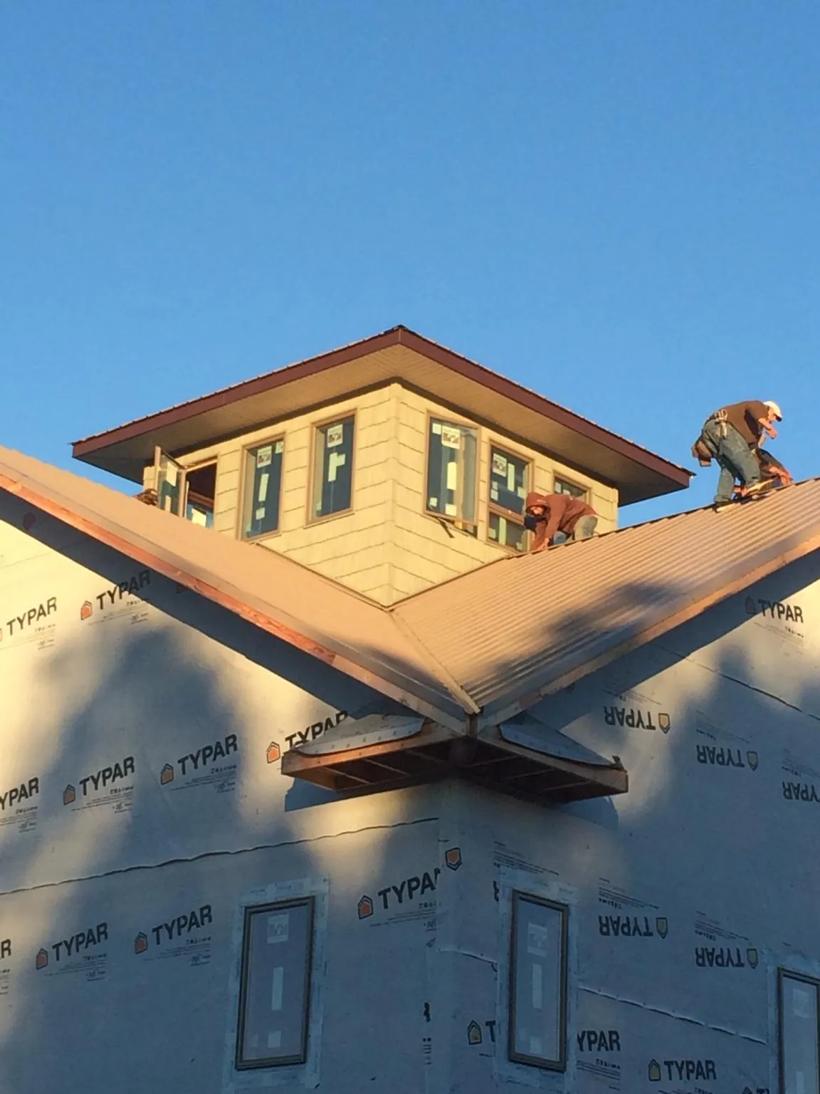 Roofers working around a rooftop cupola on a new metal roof at sunset — Roof Waterproofing in Port Barre by Roofing Brothers